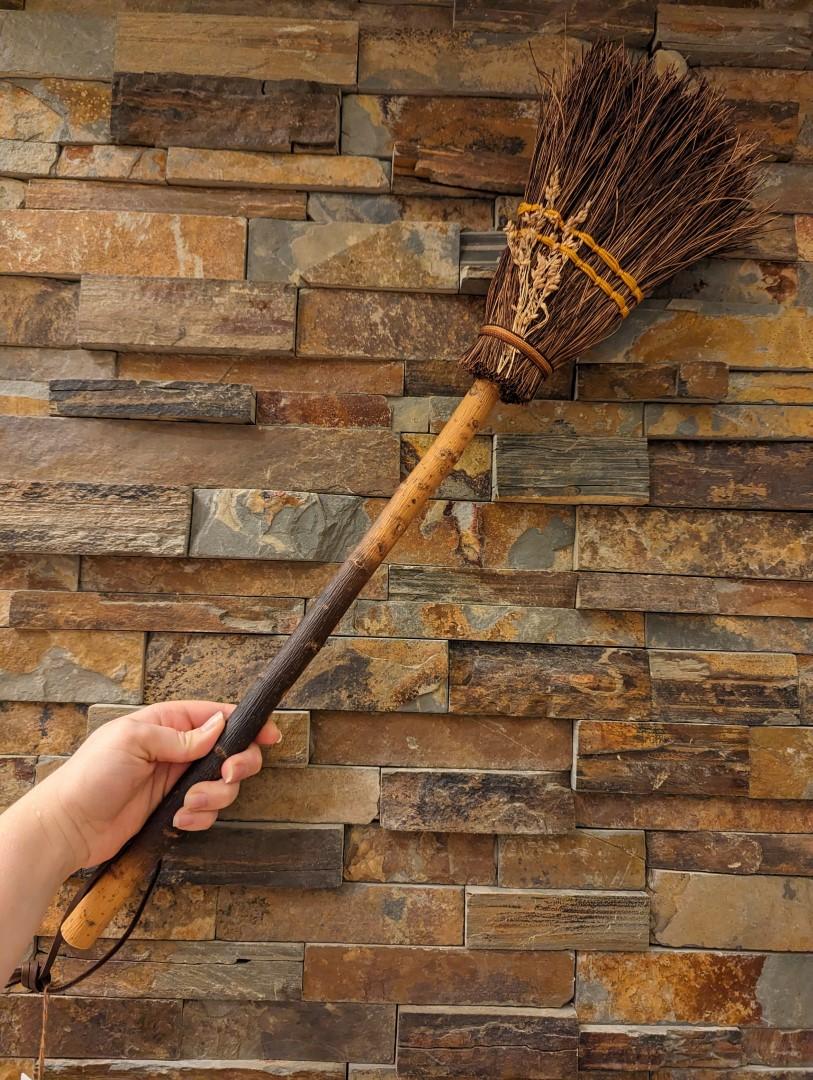 Hand holding the hearth broom against brick hearth for scale